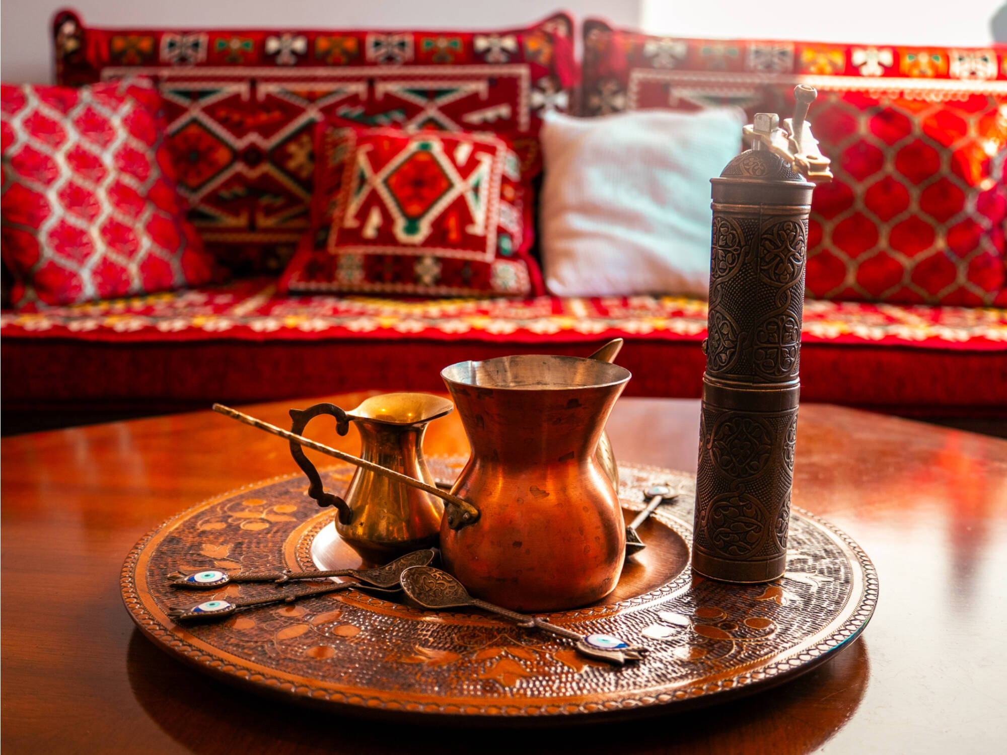 A tea set on a table with a red and gold couch in the background